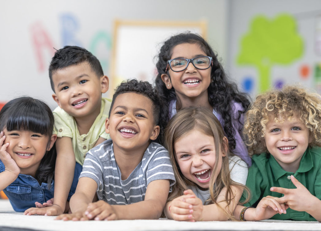 Six pre-school age children pose and smile for a picture